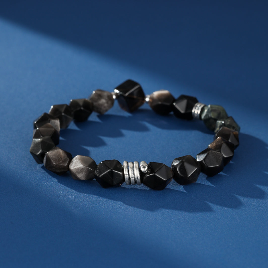 Bracelet pour homme "Esprit du Serpent" fait de pierres d'obsidienne, de quartz fumé et de jaspe Kambaba, avec des détails en argent, sur un fond bleu avec des ombres.