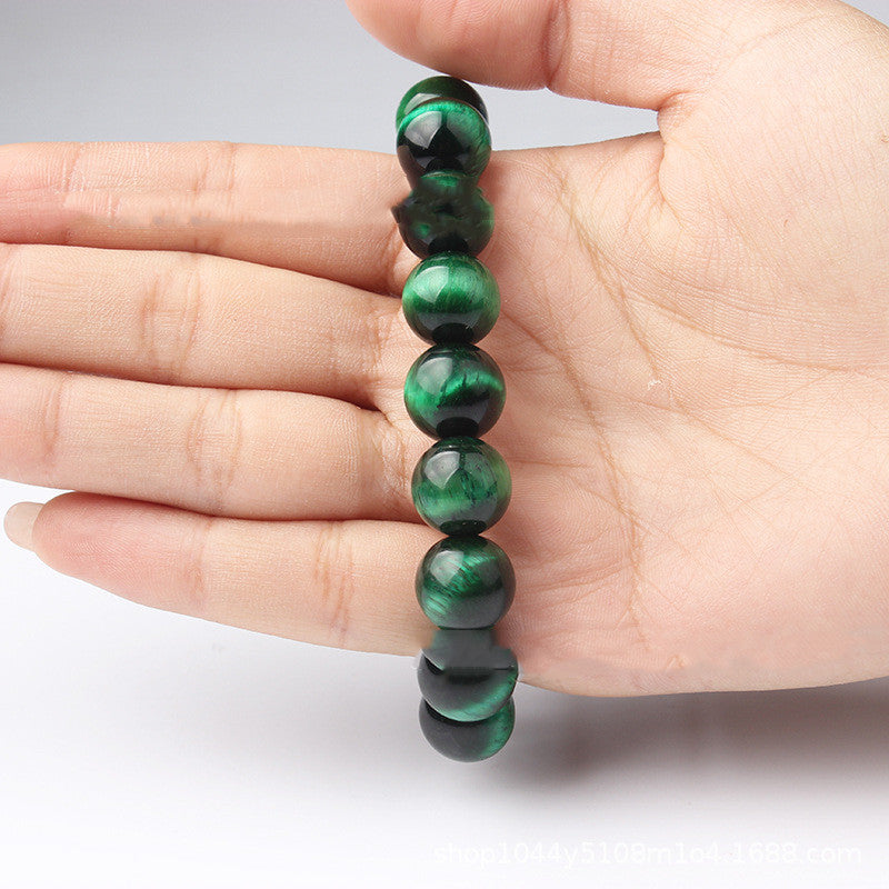 Bracelet fait de perles rondes d'œil de tigre vert, tenu dans une main