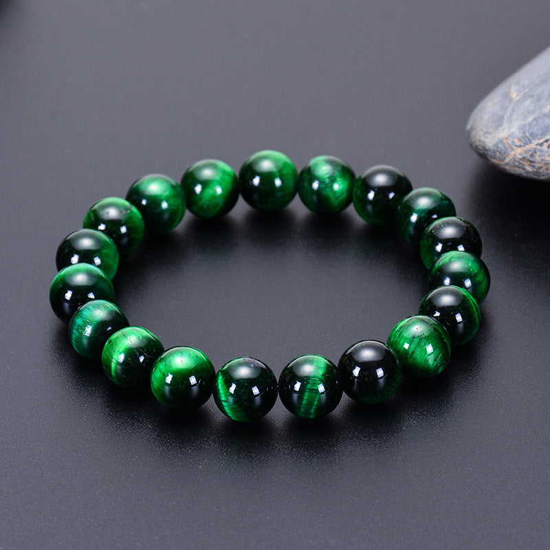 Bracelet en œil de tigre vert, composé de perles rondes polies, sur fond noir.