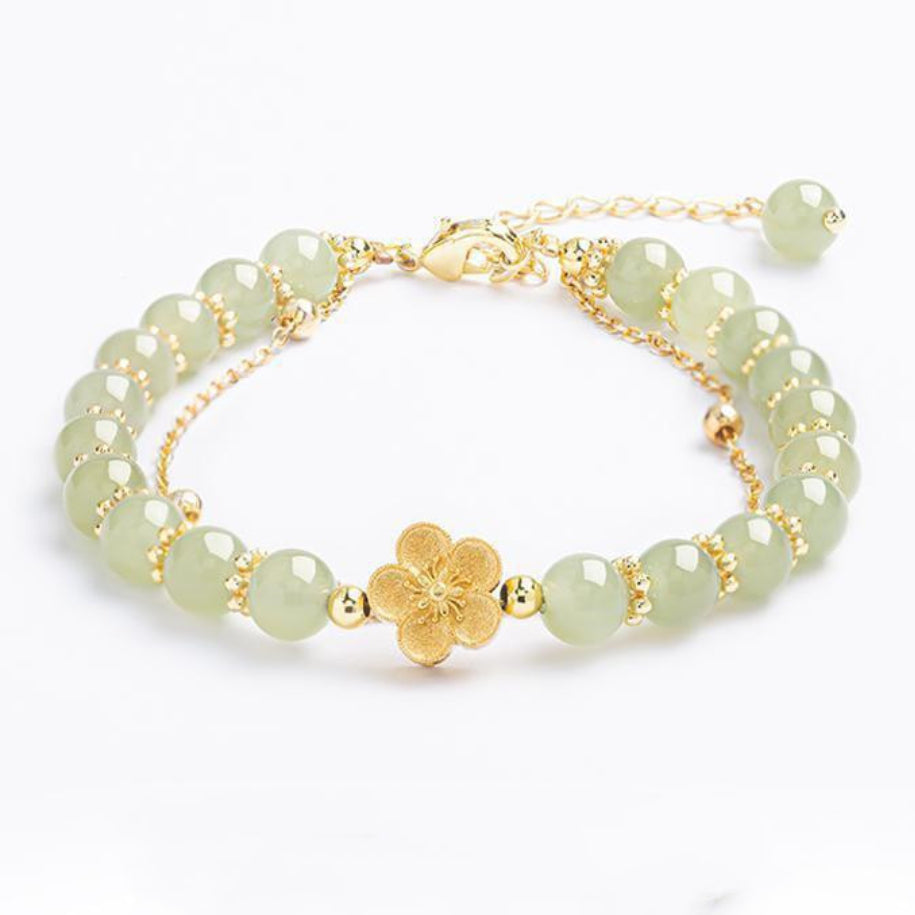 Bracelet en jade clair avec des perles dorées et un pendentif fleur de sakura doré.