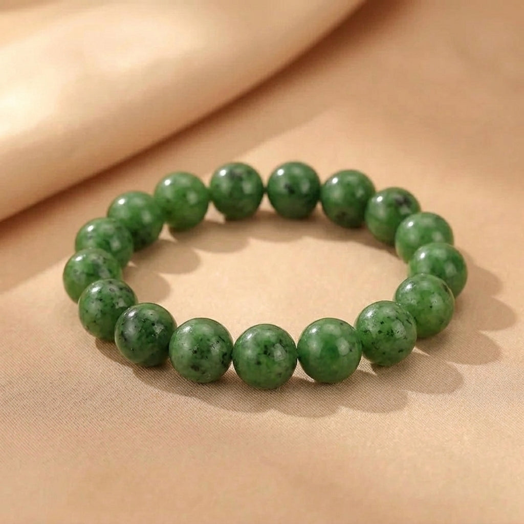 Bracelet en perles de jade vert naturel de la collection Source Secrète posé sur un tissu beige