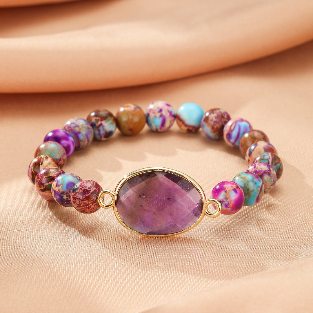 Bracelet élastique en jaspe multicolore avec une pierre centrale ovale violette facettée sertie d'or.