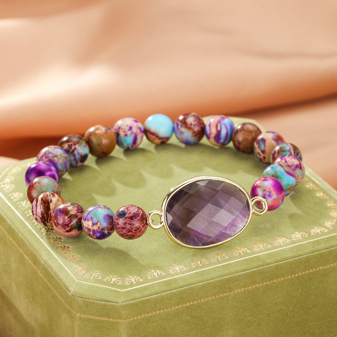 Bracelet fantaisie avec perles multicolores en jaspe et une grosse pierre centrale violette facettée, monté sur un fil élastique doré.