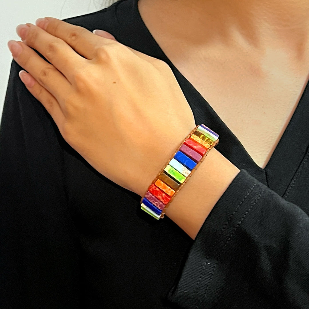 Bracelet en jaspe multicolore avec des pierres rectangulaires disposées sur un poignet féminin.