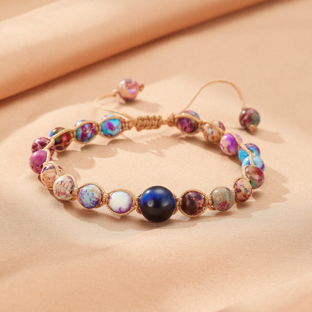 Bracelet ajusté avec des pierres jaspes multicolores et une grosse perle bleue centrale sur un cordon.