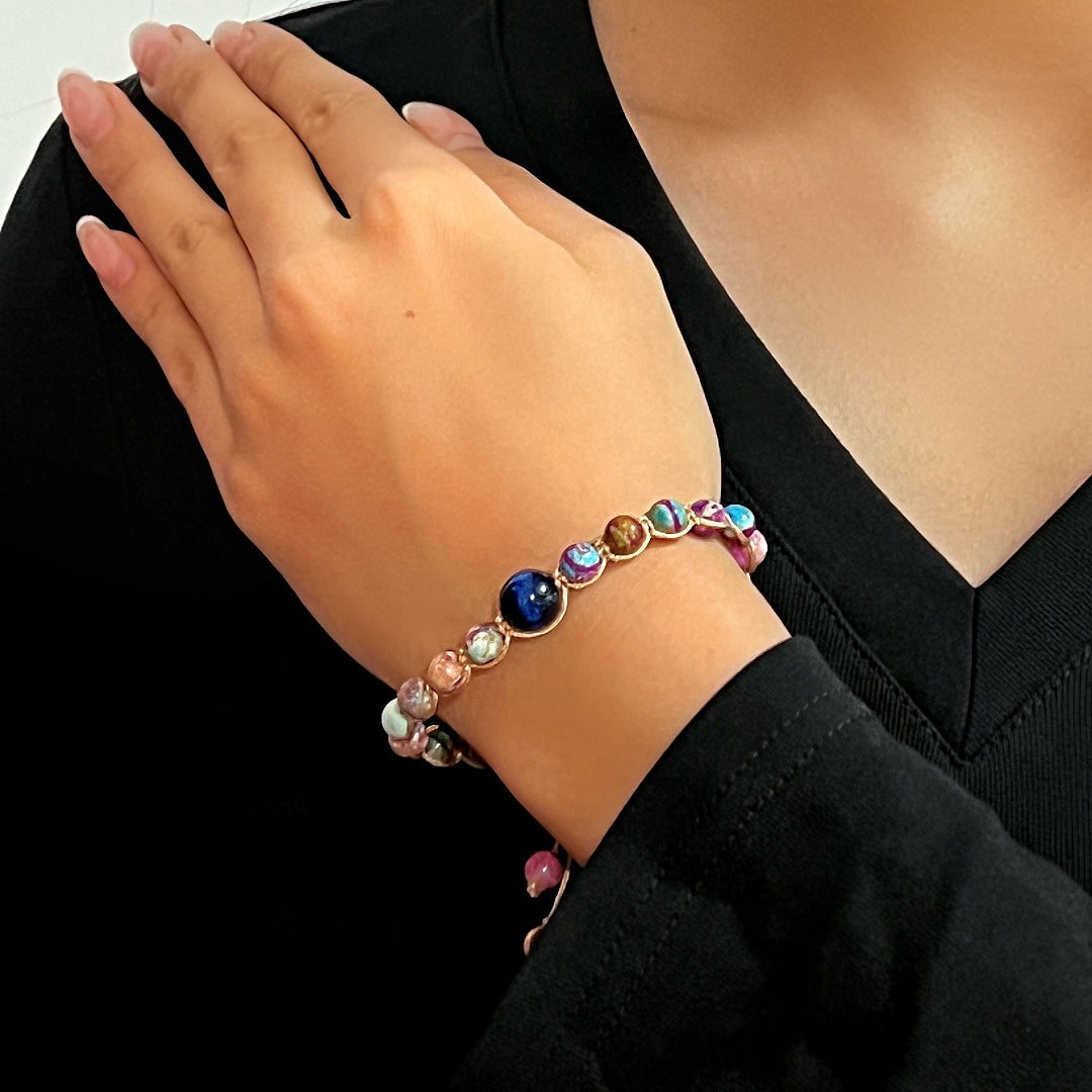 Bracelet Jaspe "Mystère Céleste" composé de perles bleues, roses, marrons et multicolores, porté au poignet d'une femme.