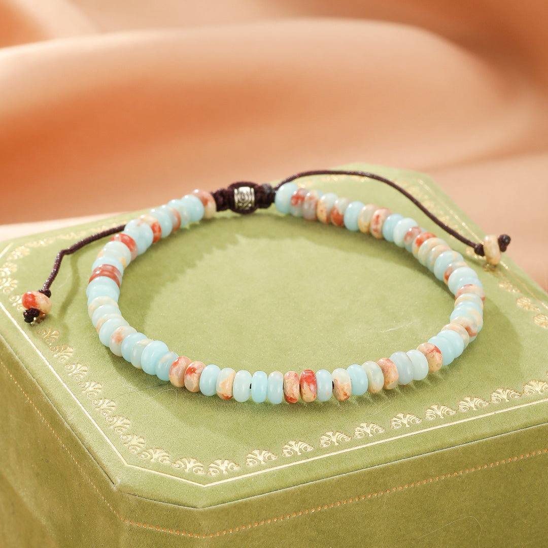 Bracelet artisanal en jaspe bleu ciel et beige avec des accents rouille, monté sur un cordon marron réglable.