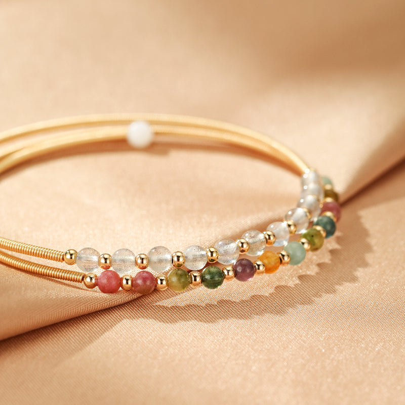 Bracelet jonc plaqué or 14K "Symphonie Minérale" orné de deux rangées de petites pierres naturelles multicolores, incluant la labradorite et la tourmaline, séparées par des perles dorées.