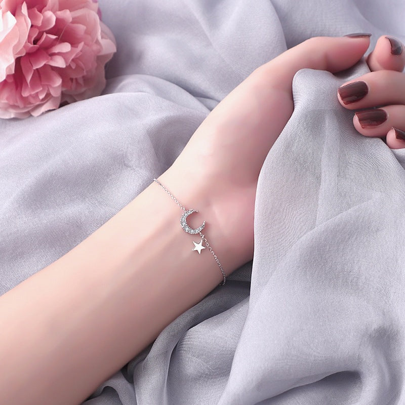 Bracelet en argent avec un pendentif en forme de lune sertie de strass et une petite étoile suspendue