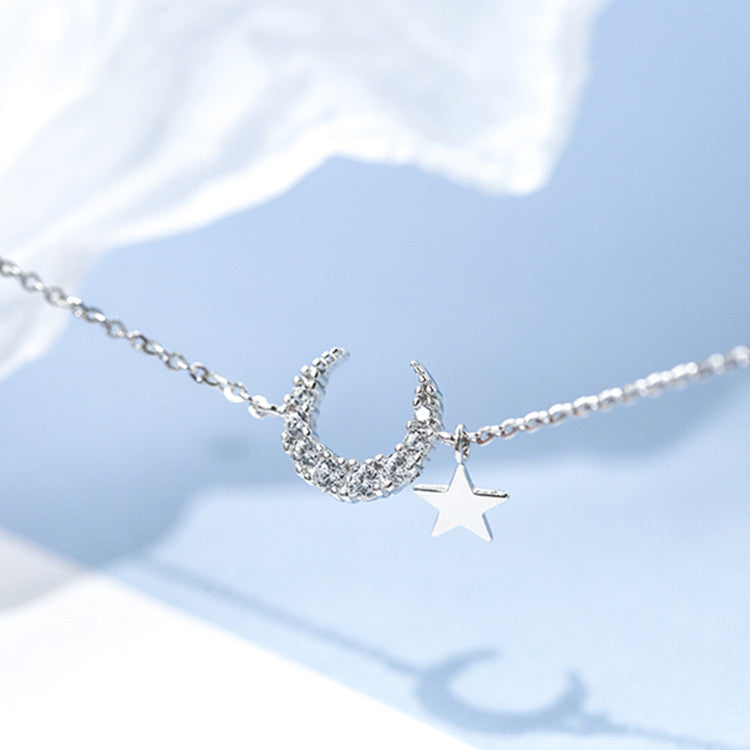 Bracelet "Rêveuse" en argent avec un pendentif en forme de croissant de lune serti de cristaux et une étoile suspendue.