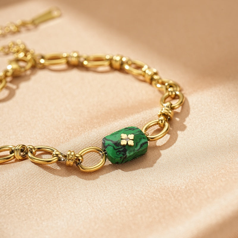 Bracelet Esprit Libre en plaqué or avec une pierre de malachite verte facettée ornée d'un motif de trèfle à quatre feuilles.