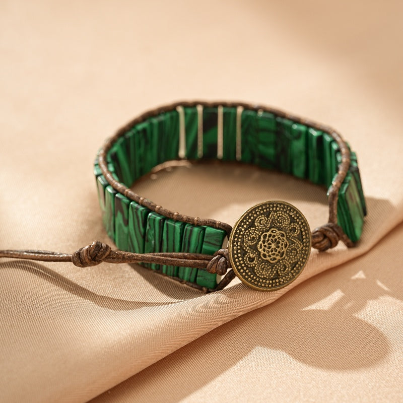 Bracelet en malachite verte avec fermoir rond en bronze patiné, monté sur cordon en cuir marron.