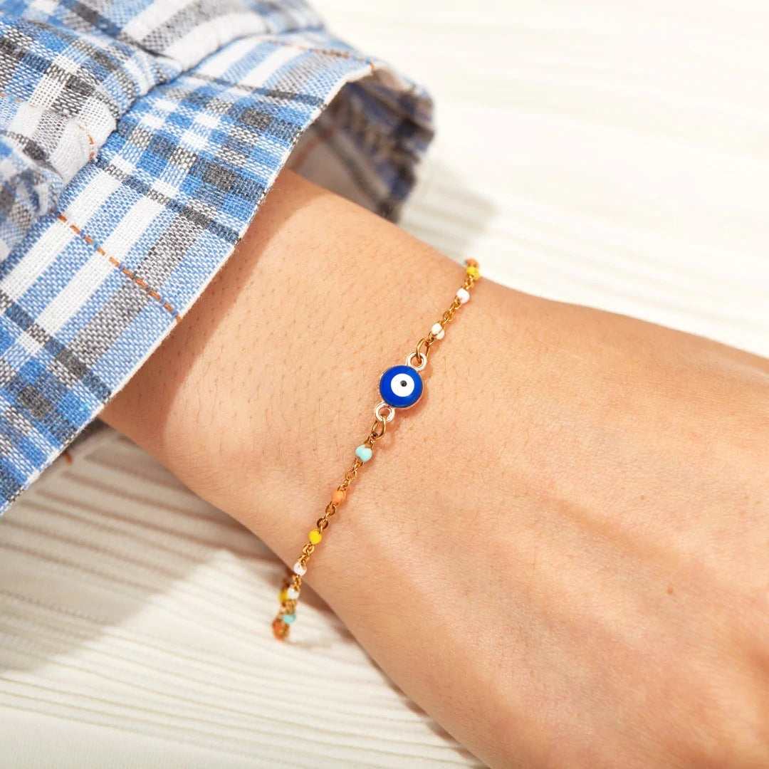 Bracelet fin en argent 925 avec un œil bleu central et de petites perles colorées sur un poignet