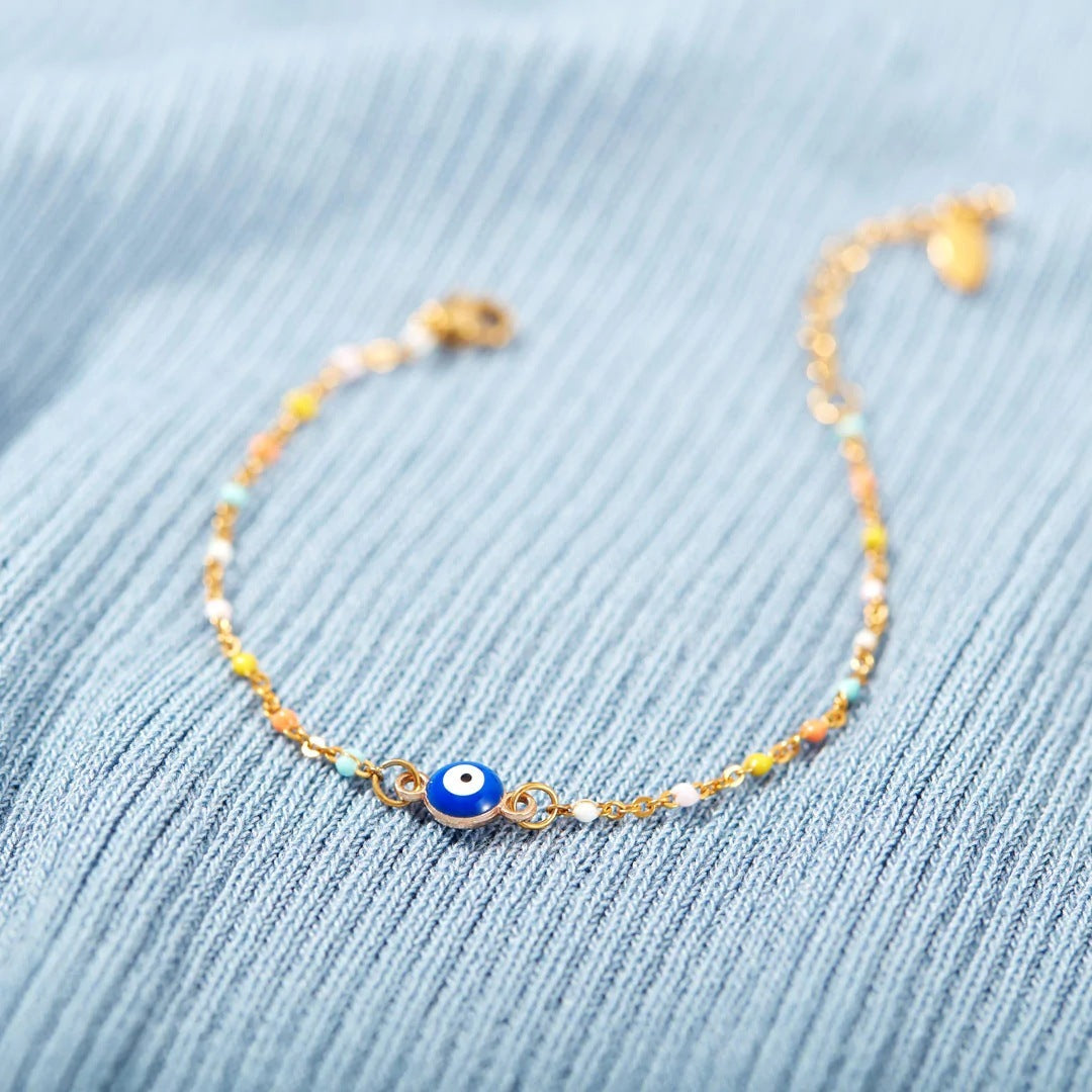 Bracelet fin en argent 925 avec un œil bleu au centre et de petites perles colorées sur la chaîne.