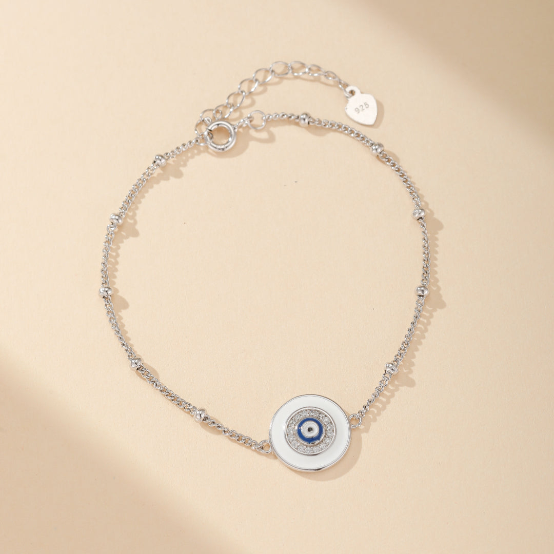 Bracelet en argent 925 avec un pendentif œil bleu et blanc, orné de petites perles argentées le long de la chaîne.