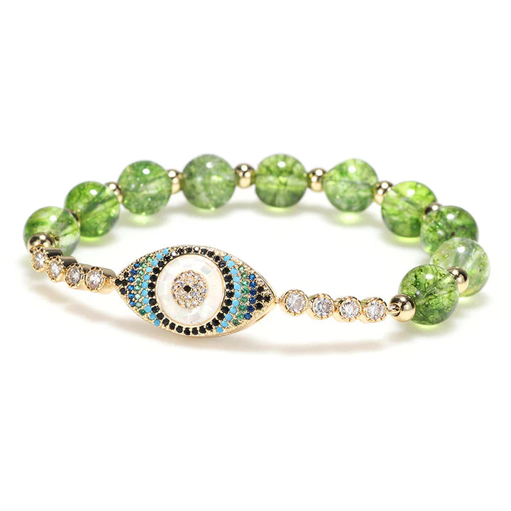 Bracelet œil du mal en peridot vert avec des pierres blanches et bleues, sur fond blanc.