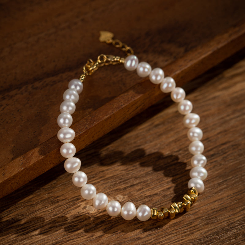 Bracelet en perles d'eau douce avec des accents en argent plaqué or, sur fond de bois rustique