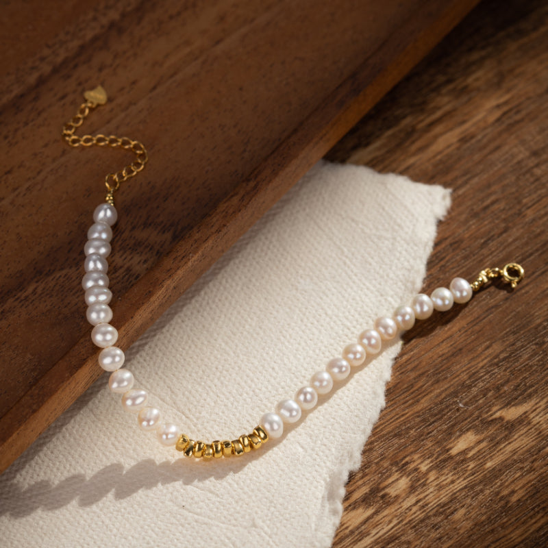 Bracelet en argent plaqué or avec des perles d'eau douce et des accents dorés, fermoir mousqueton réglable.