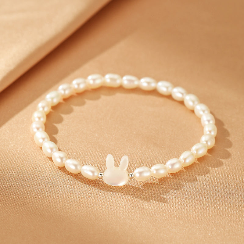 Bracelet perle avec un pendentif tête de lapin en nacre, monté sur un fil agrémenté de perles d'eau douce.