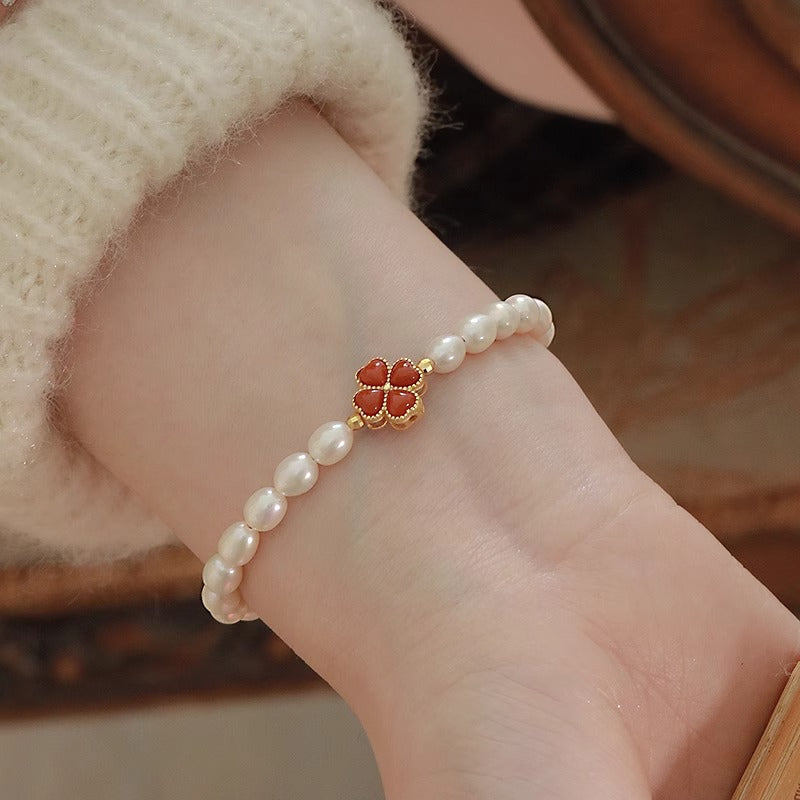 Bracelet en argent plaqué or avec des perles d'eau douce et un charmant trèfle rouge au centre.