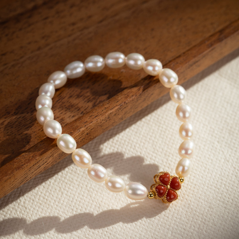 Bracelet en perles d'eau douce avec un charmant trèfle en corail rouge et fermoir plaqué or.