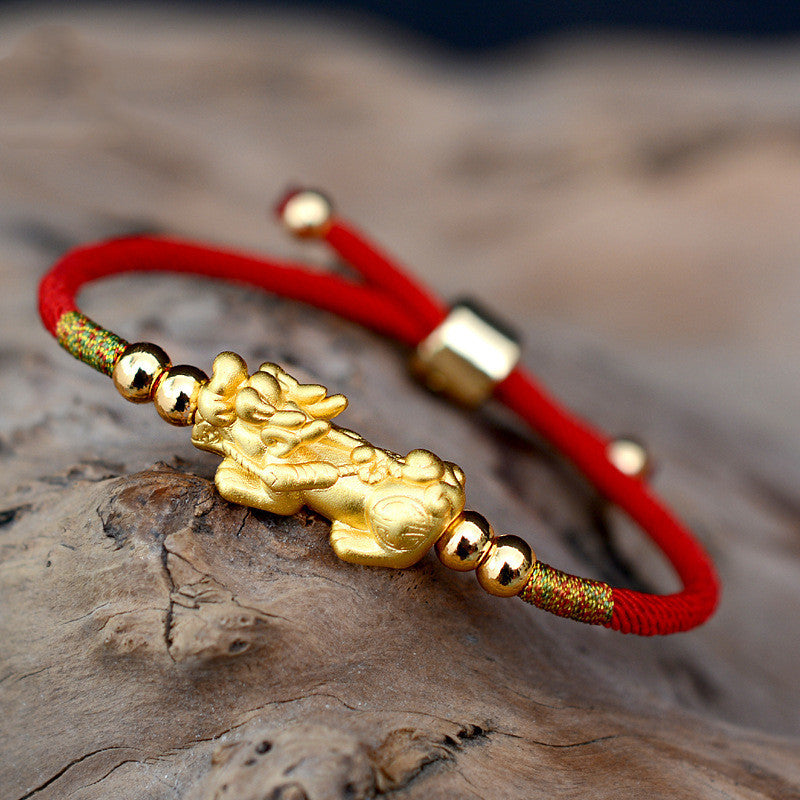 The "Mythique" bracelet in Red Thread and Pi Xiu symbol placed on a rock