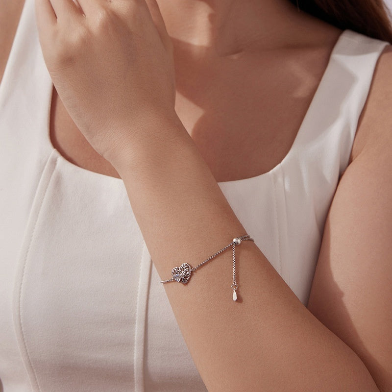 Bracelet ajustable en argent orné d'un pendentif Arbre de Vie scintillant, porté au poignet d'une femme.