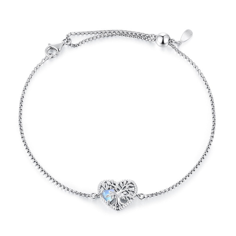 Bracelet en argent orné d'un pendentif en forme de cœur ajouré représentant l'Arbre de Vie, avec une pierre de lune bleue irisée.