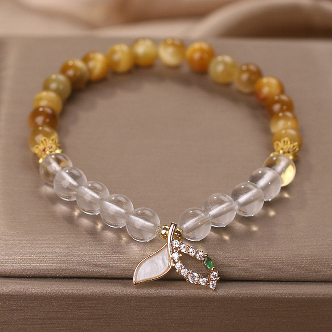 Bracelet fait de perles de quartz clair et d'œil de tigre, orné d'un pendentif feuille nacrée et d'une pierre verte entourée de diamants.