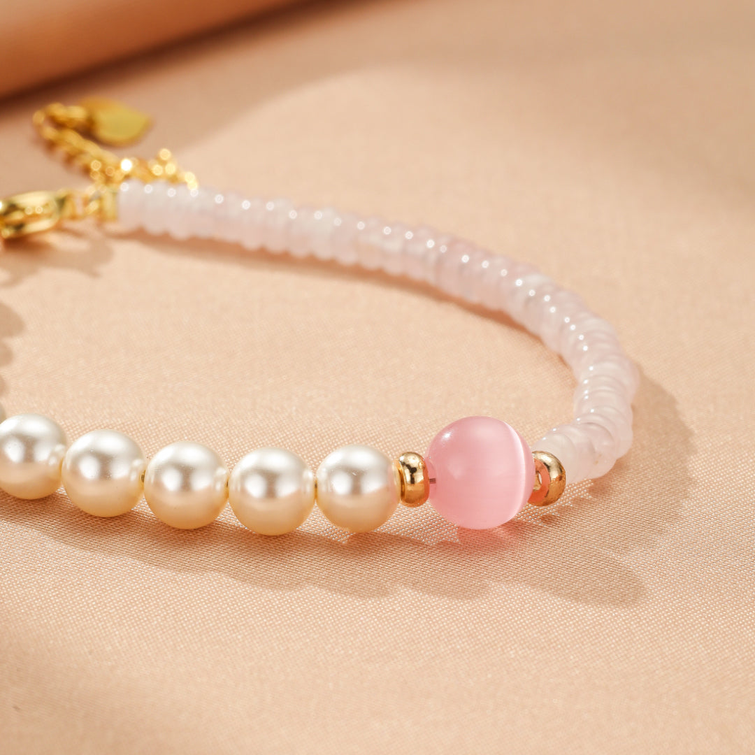 Bracelet élégant avec des perles nacrées, des perles de quartz rose et une perle centrale rose, rehaussé de petits détails dorés.