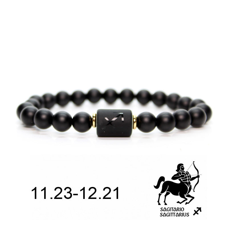 Bracelet en onyx noir avec un pendentif rectangulaire noir gravé du signe astrologique du Sagittaire, bordé de perles dorées. Dates du Sagittaire : 11.23-12.21.