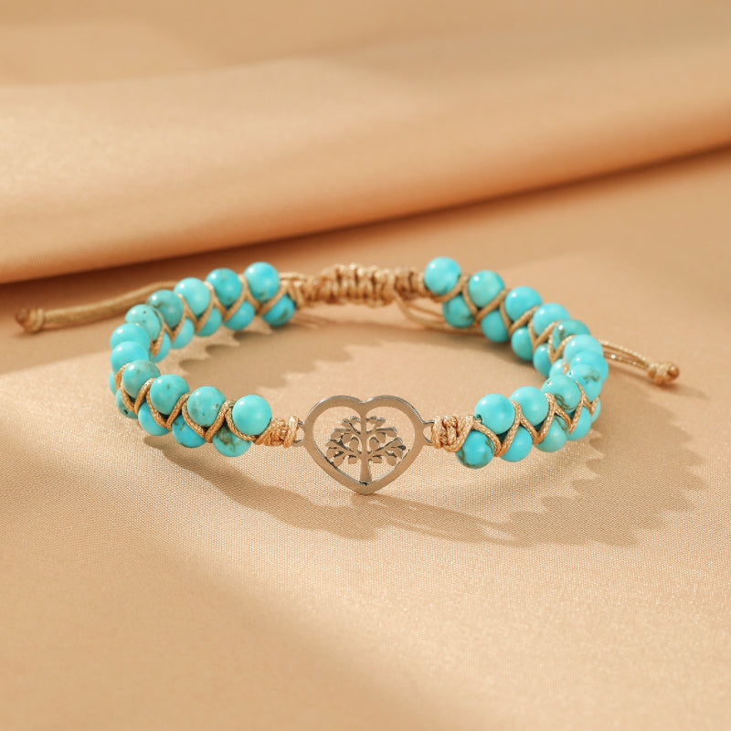 Bracelet en turquoise avec un pendentif Arbre de Vie en forme de cœur, monté sur un cordon tressé de couleur beige.