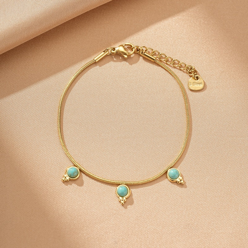 Bracelet turquoise sur chaîne dorée fine, orné de trois petites pierres bleues turquoise, fermoir à mousqueton et chaîne d'extension.