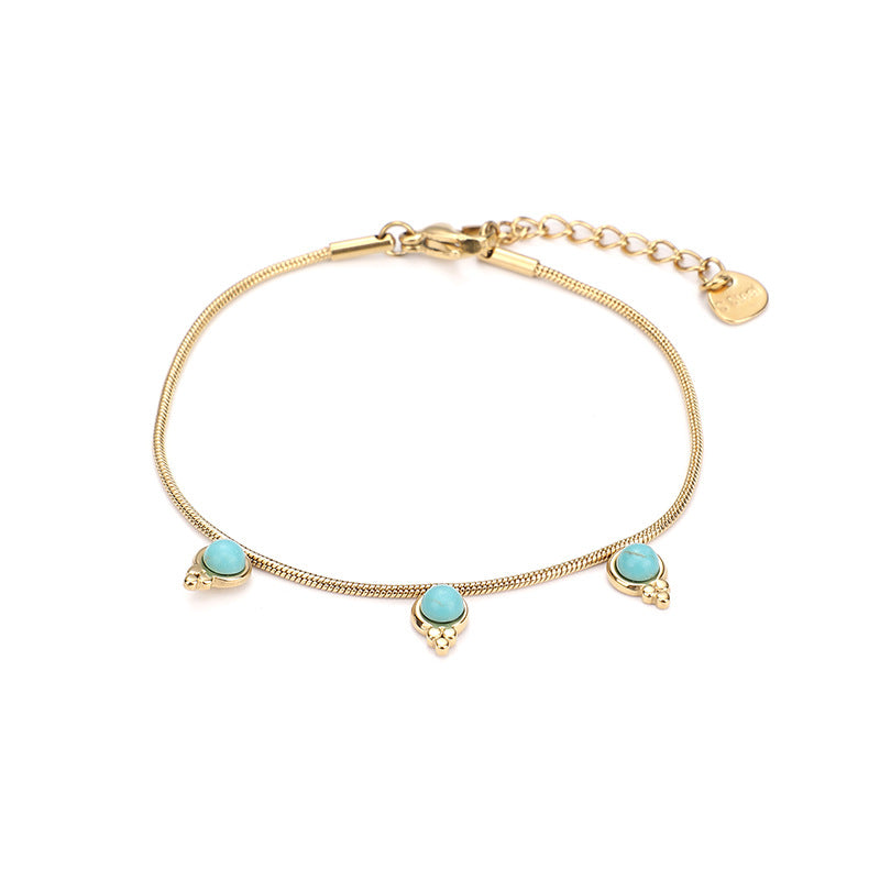 Bracelet fin doré avec trois pierres turquoise rondes disposées sur la chaîne serpentine, style bohème chic.