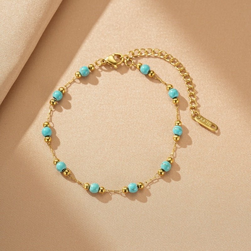 Bracelet fin en or avec perles turquoise et petites perles dorées, fermoir mousqueton et chaînette d'extension.