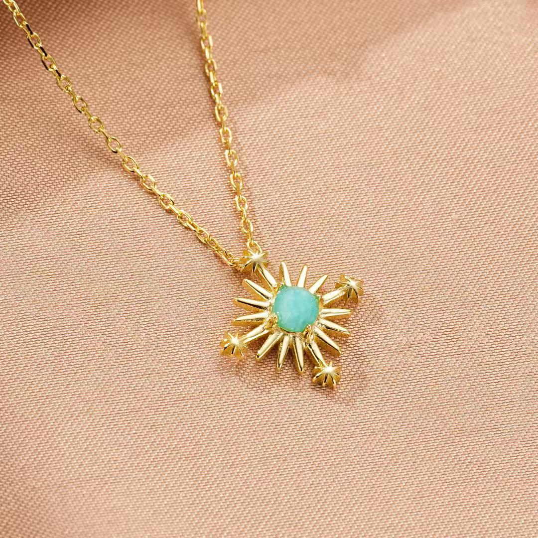 Collier tendance en argent plaqué or, orné d'une pierre d'amazonite turquoise au centre et d'une croix étoilée aux rayons dorés.