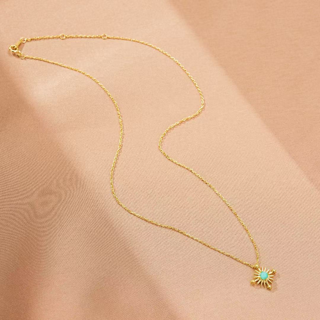 Collier en argent plaqué or avec un pendentif en forme de croix étoilée ornée d'une petite pierre d'amazonite bleue.