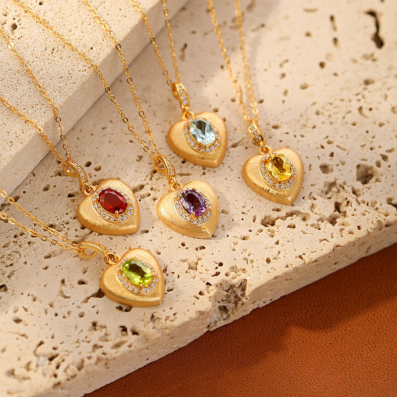 Cinq colliers en forme de cœur avec différentes pierres précieuses (améthyste, citrine, topaze, péridot, grenat) et monture en argent plaqué or, ornés de petits diamants.