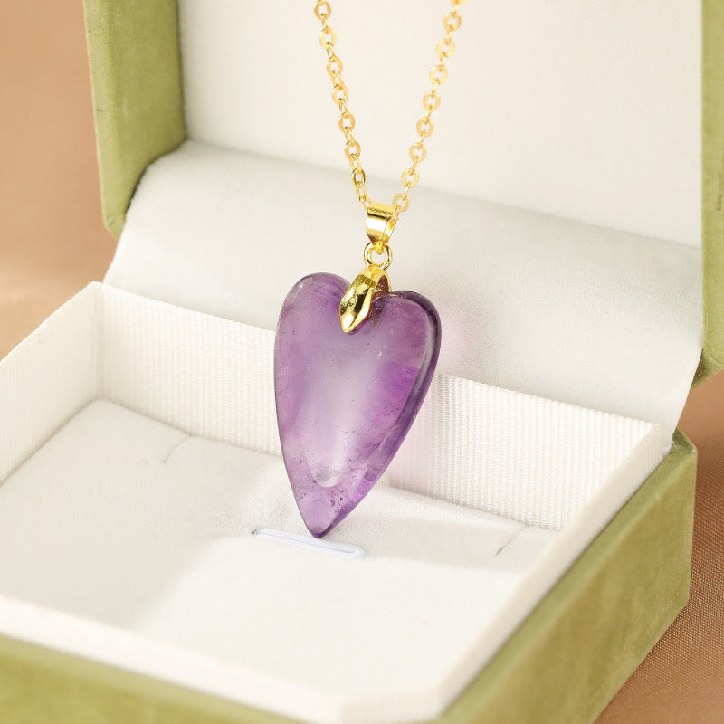 Collier doré avec pendentif en forme de cœur en améthyste violette, présenté dans une boîte cadeau verte.
