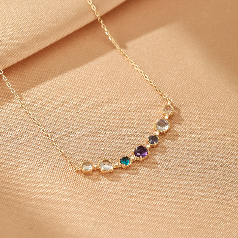 Collier plaqué or en forme d'arc de cercle orné de multiples pierres gemmes colorées, dont une améthyste violette, disposées sur une fine chaîne dorée.
