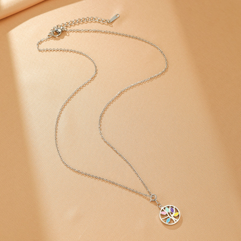 Collier Arbre de Vie en argent avec un pendentif rond orné d'un arbre aux feuilles multicolores, posé sur un fond beige.
