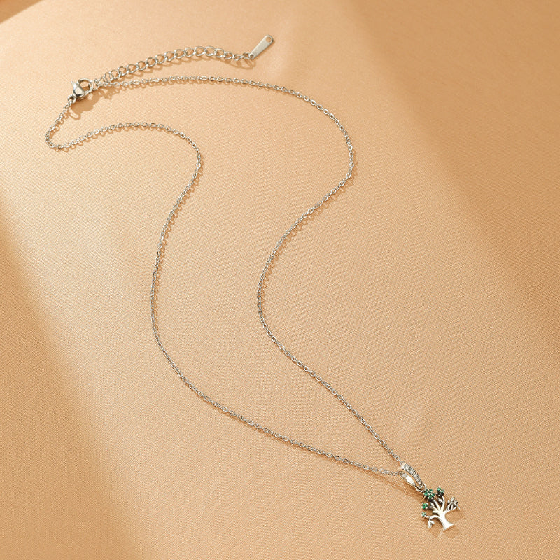 Collier Arbre de Vie en argent avec un pendentif orné de petites pierres vertes symbolisant l'énergie de la terre.