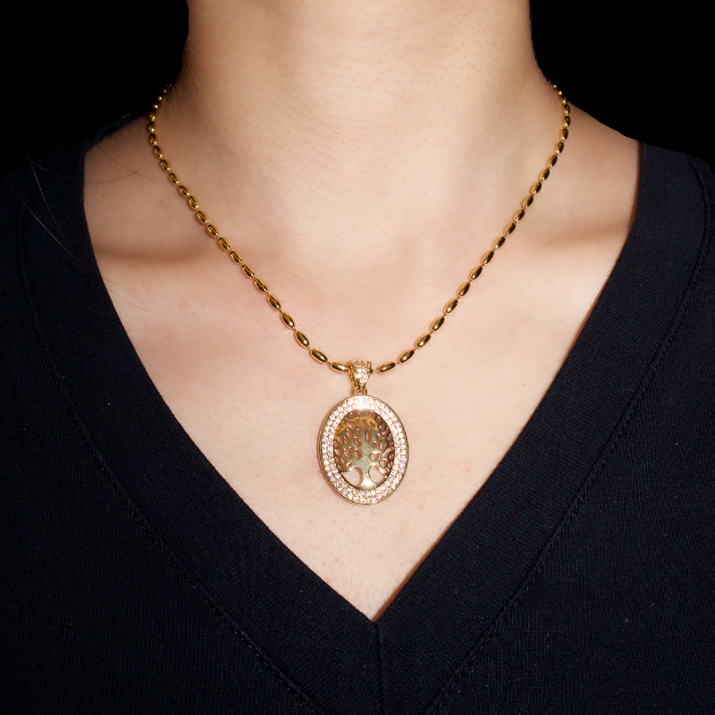 Collier Arbre de Vie en or jaune avec un pendentif ovale serti de zircons et représentant un arbre de vie stylisé, porté par une femme.