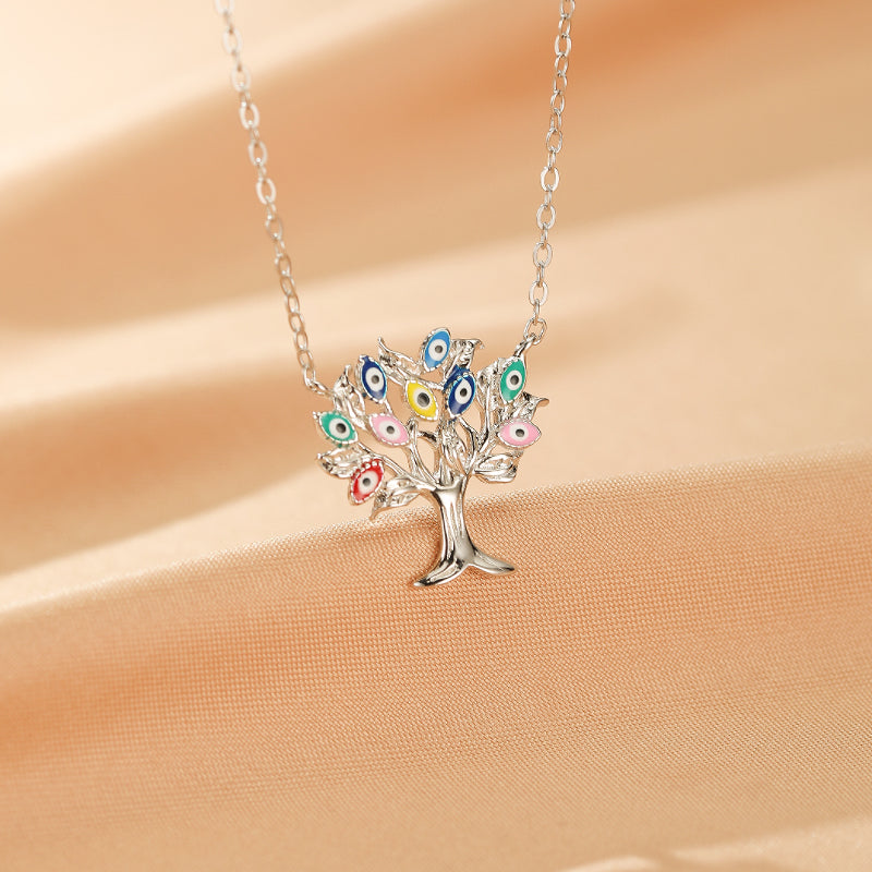 Collier Arbre de Vie en argent 925 orné de multiples "mauvais yeux" multicolores (bleu, rose, jaune, vert, rouge) sur un fond de tissu satiné beige.