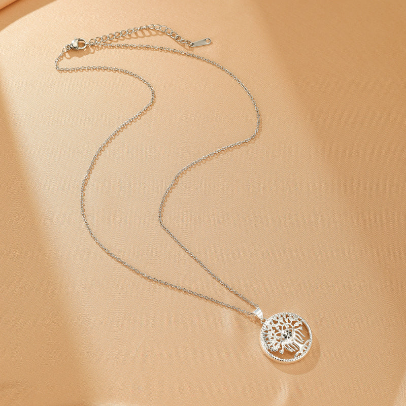Collier Arbre de Vie en argent avec pendentif ajouré représentant un arbre stylisé avec des racines et des branches, posé sur un fond beige texturé.
