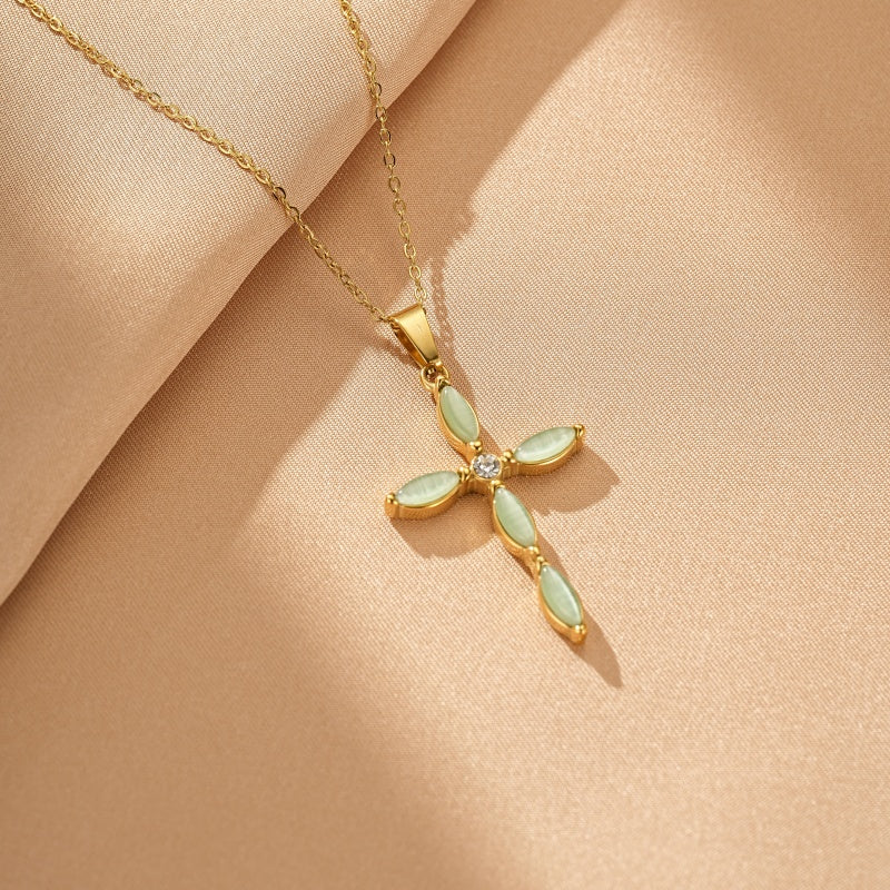 Collier en or avec un pendentif en forme de croix orné de pierres d'aventurine vertes et d'un petit cristal au centre.