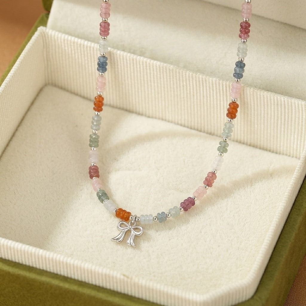 Collier "Nœud de Bonheur" en pierres fines colorées, incluant de l'aventurine, du jade, de l'aigue-marine et du quartz fraise, avec un pendentif nœud argenté.