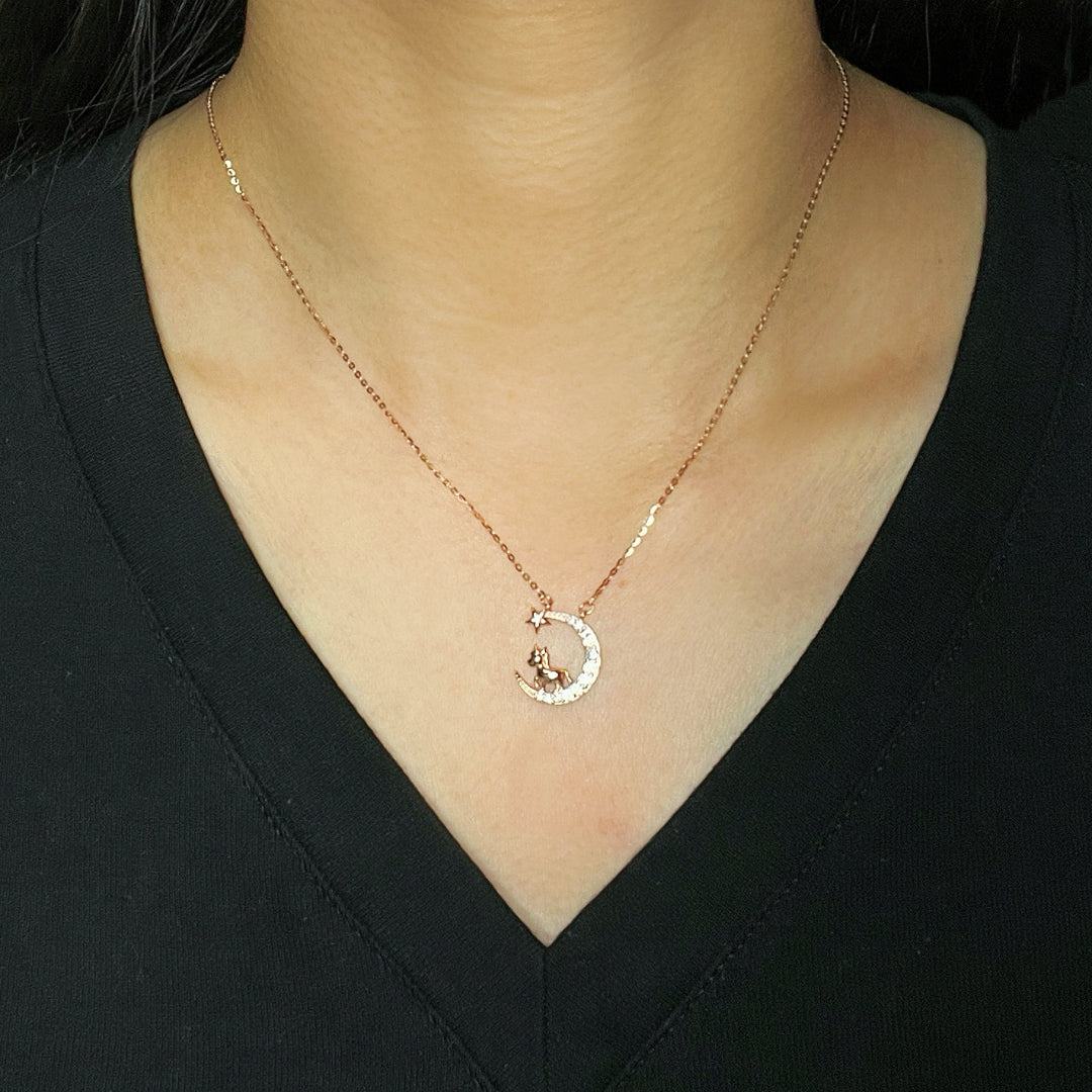 Collier en argent plaqué or rose avec un pendentif en forme de croissant de lune orné de zircons et d'une petite étoile, avec une figurine de cheval assise sur la lune.