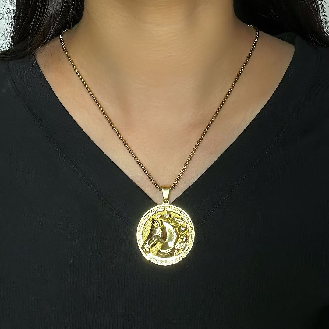 Pendentif rond doré avec une tête de cheval gravée en relief, monté sur une chaîne à maillons fins.