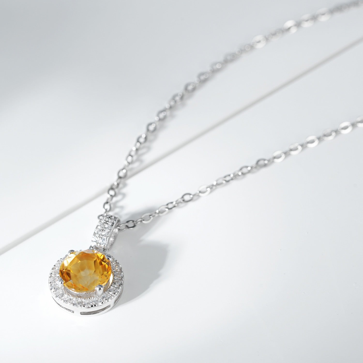 Collier en argent 925 avec un pendentif rond serti d'une citrine centrale entourée de zirconiums cubiques scintillants, monté sur une fine chaîne.